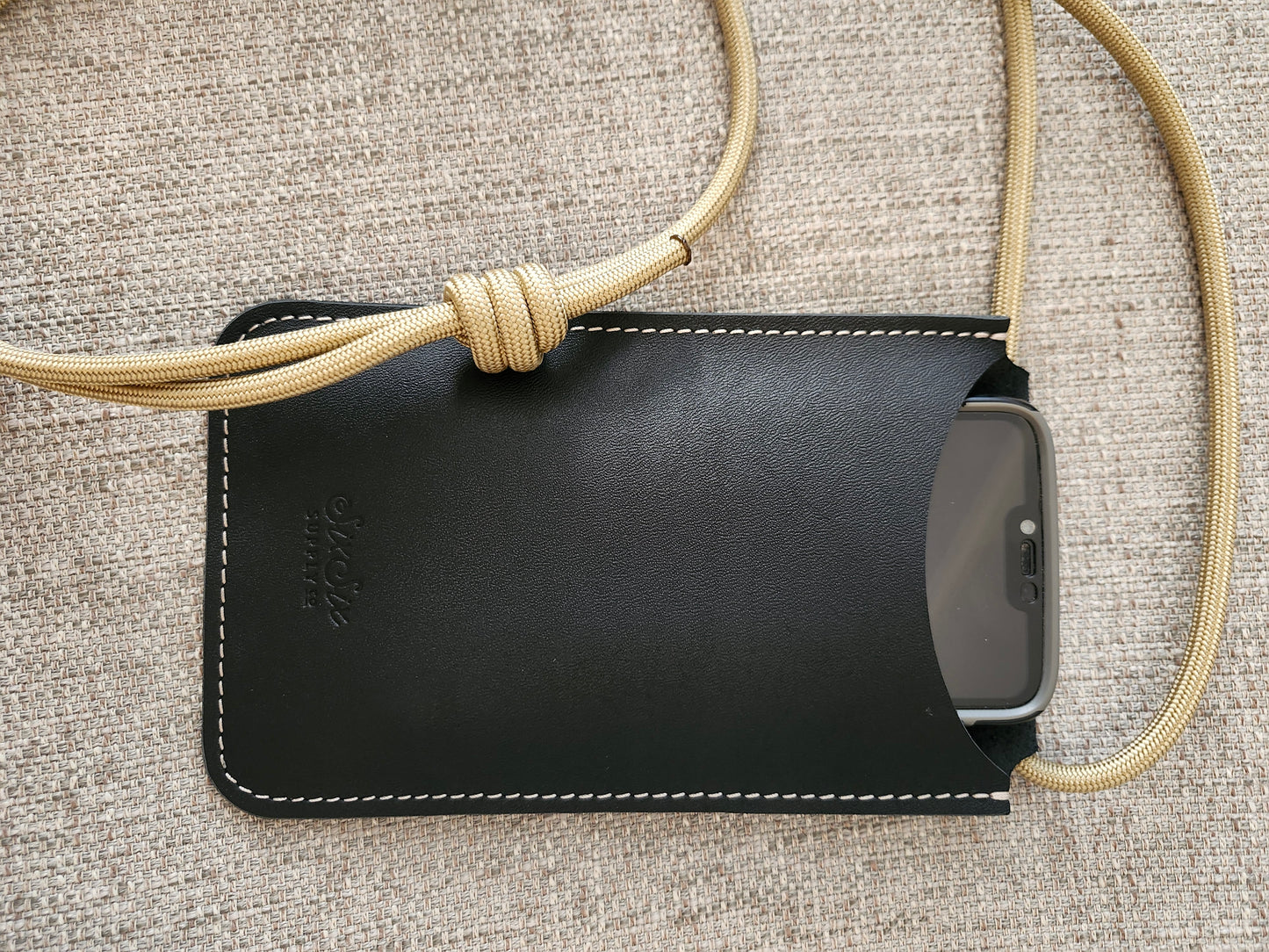 Black phone case with a lanyard on a textured surface